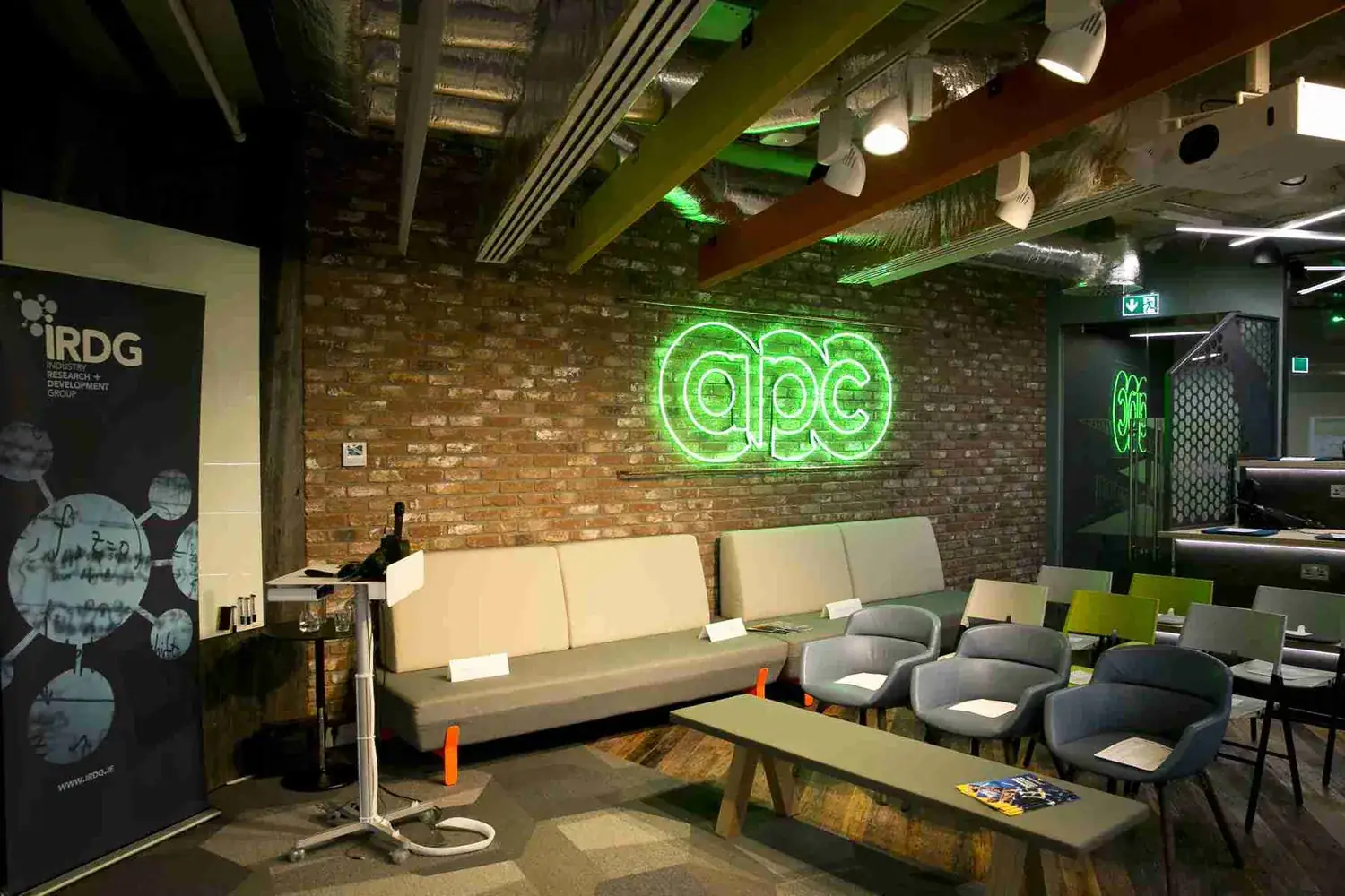 The APC innovation centre in Dublin — an open presentation space with APC's illuminated sign on the wall.